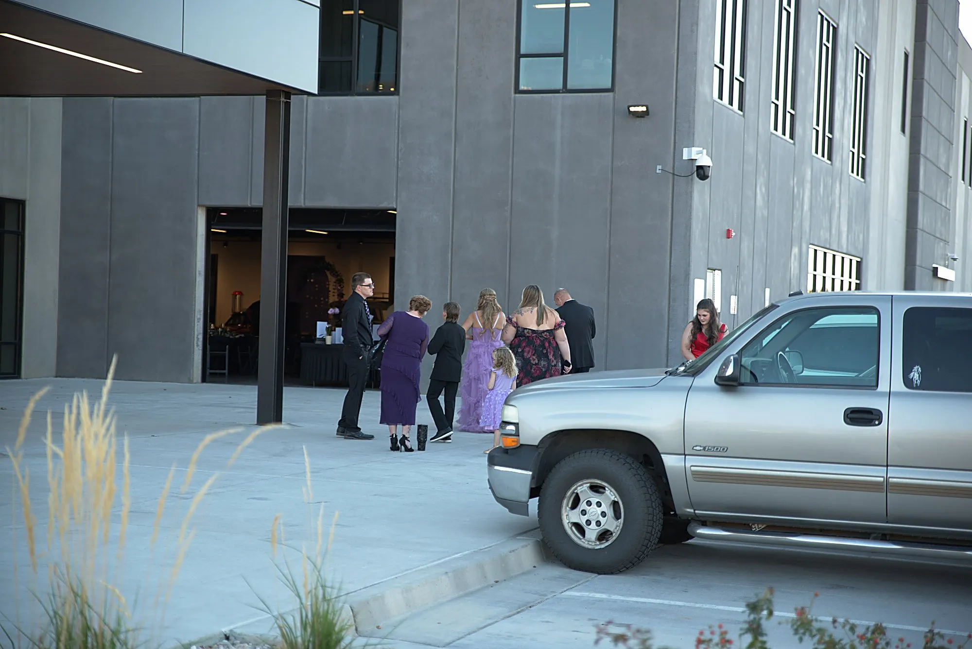 Guests arriving under the entrance canopy beside a pickup at dusk