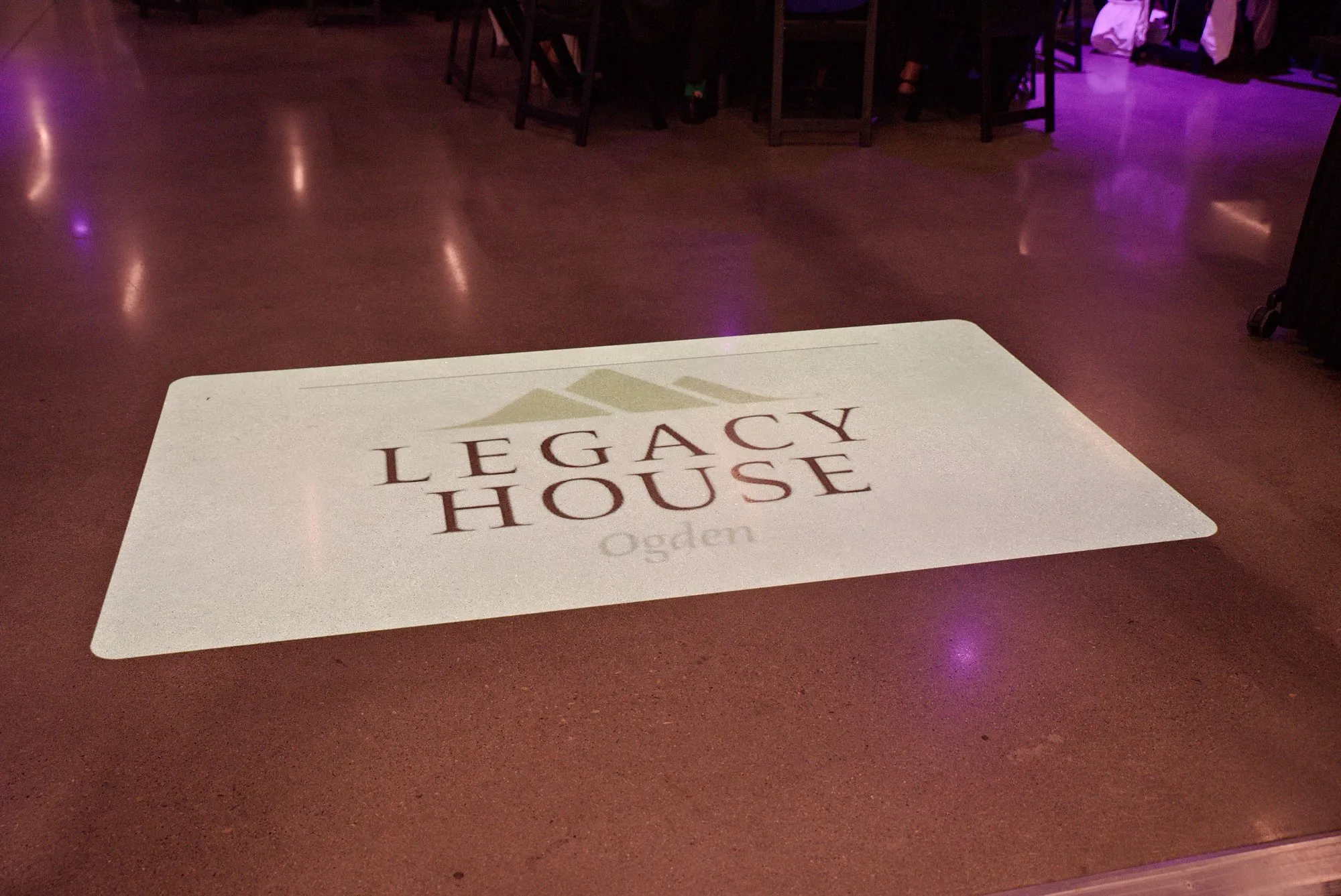 A sponsor logo projected onto the polished showroom floor in purple light