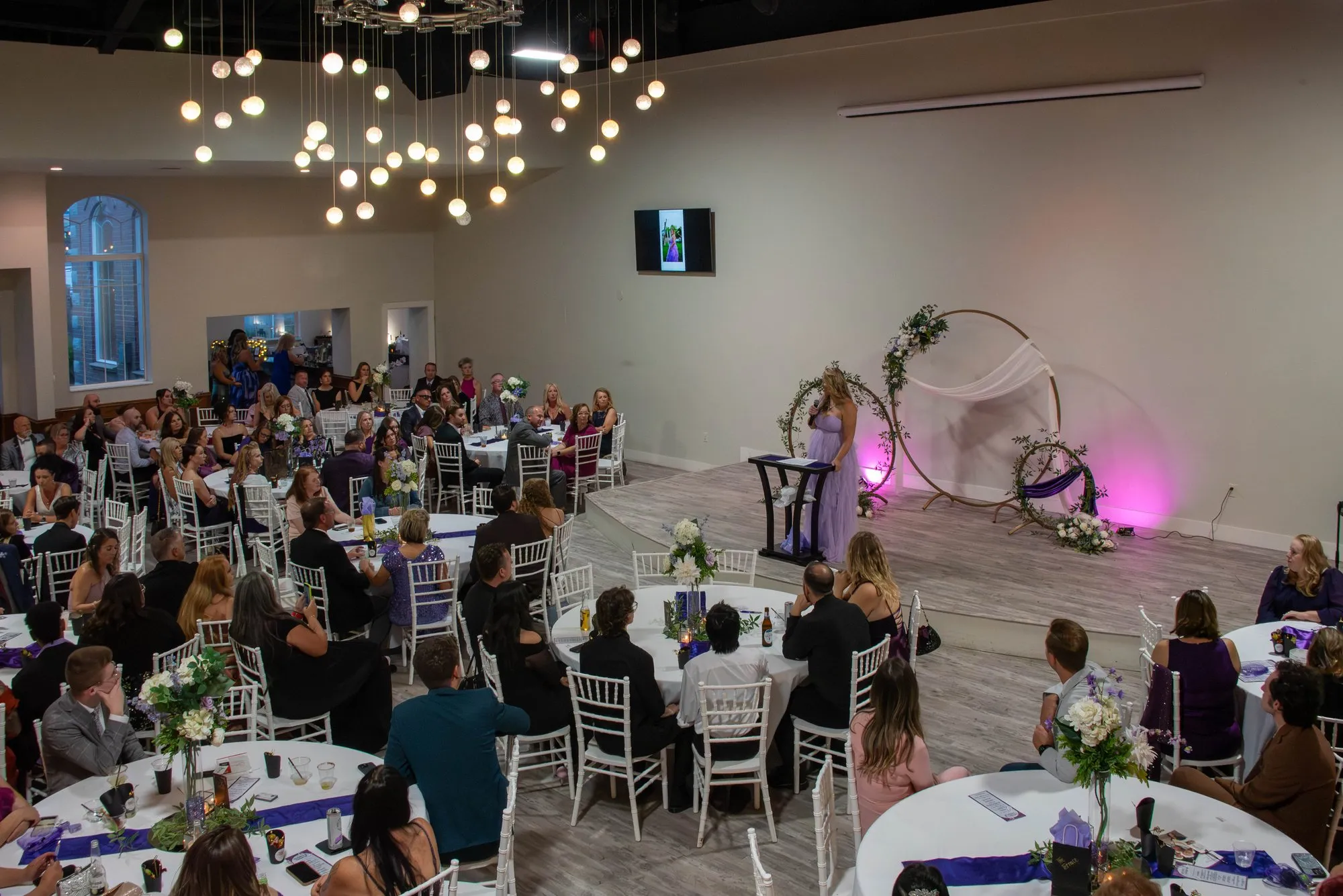 Wide view of the gala room during the program, chandeliers overhead