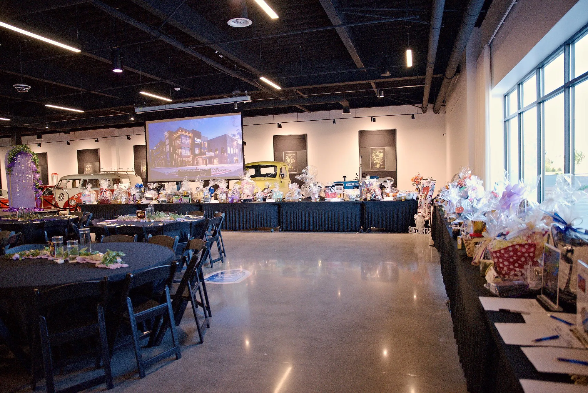 The gala room before guests arrive, round tables dressed in black with a long auction table