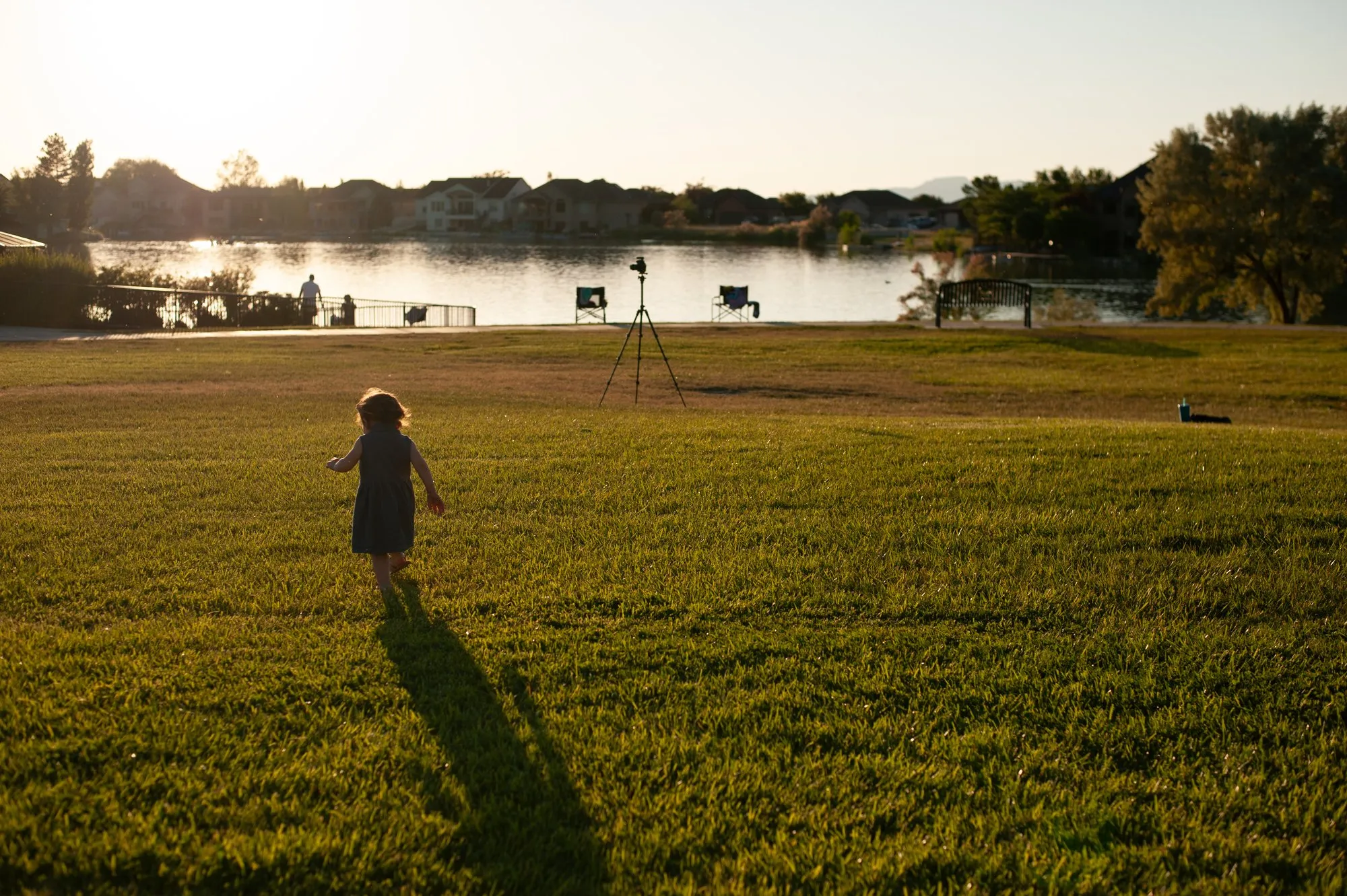 Small girl running across the lawn, casting a long evening shadow