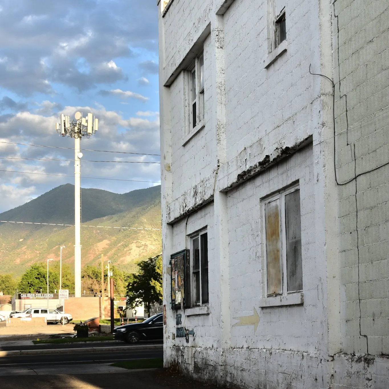 Weathered white building against the mountains and a bright sky